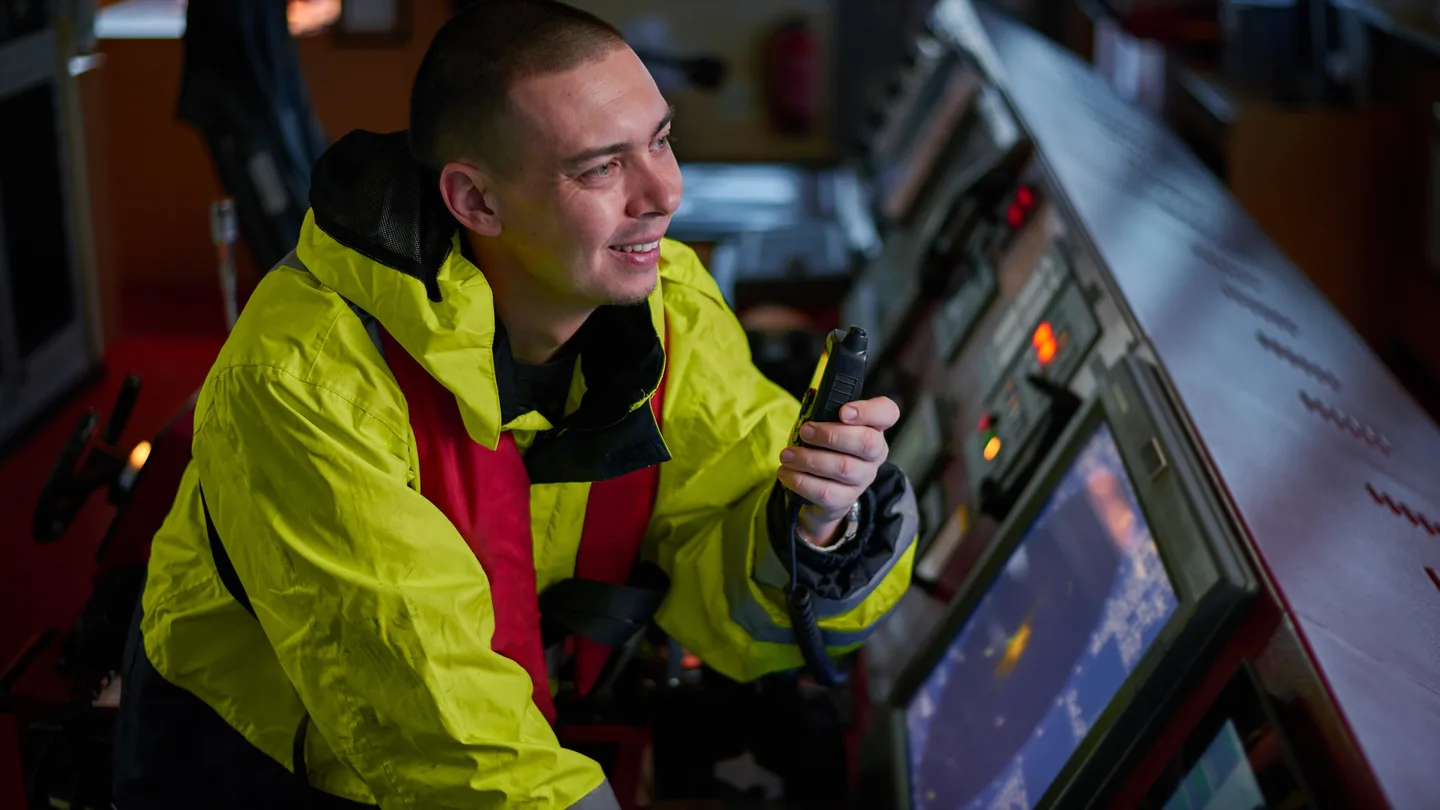 Maritime operator using a handheld radio on a vessel bridge